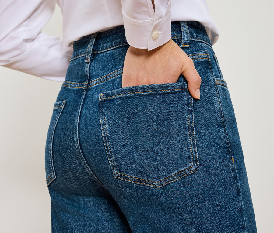 Pohľad zozadu na ženu s rukou vo vrecku modrých Mom Jeans – Fit »Nyla«.