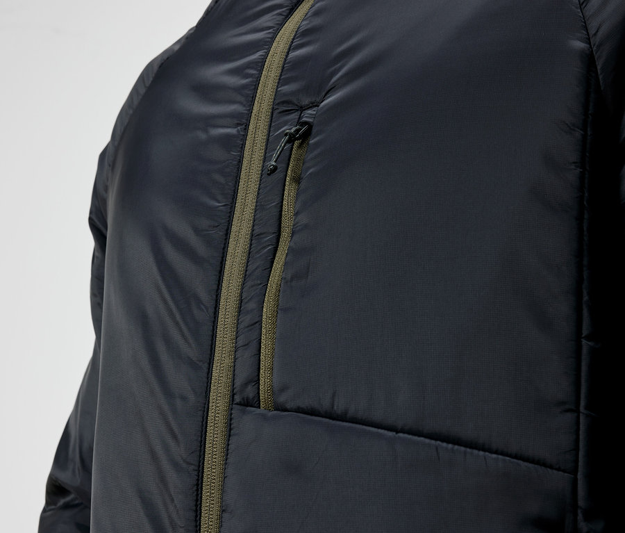 Detail čiernej prešívanej bundy so zeleným zipsom.