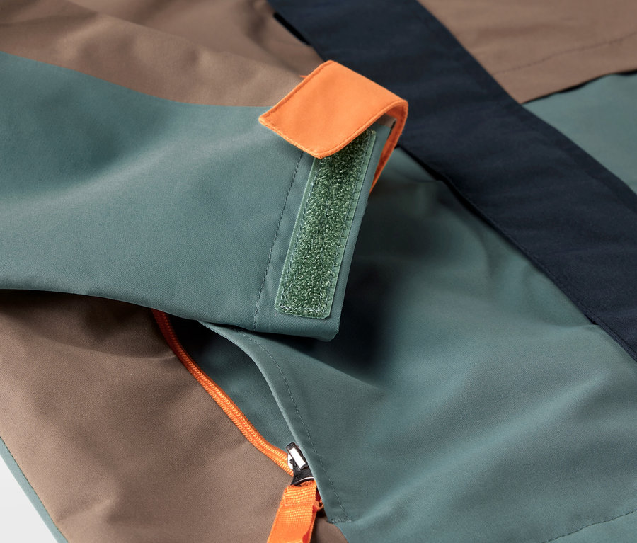 Detail detskej bundy do každého počasia s vreckom na zips a manžetou na suchý zips.