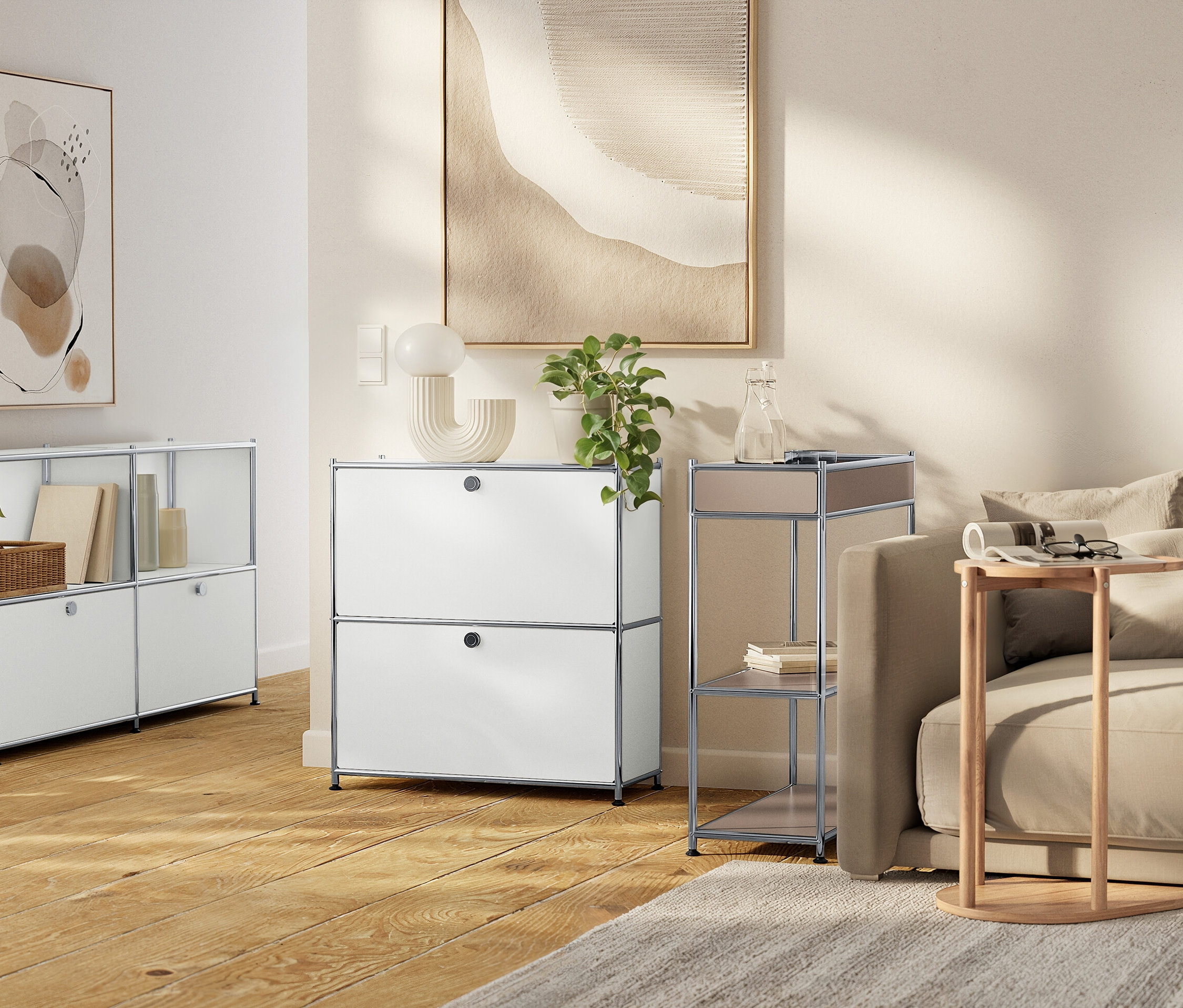 Obývacia izba s bielymi modulárnymi úložnými jednotkami, béžovou pohovkou a neutrálnymi umeleckými dielami.