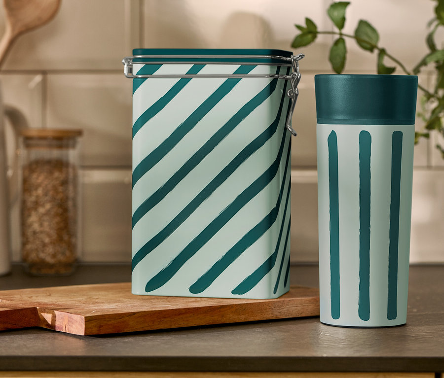 Na kuchynskom stole stojí prúžkovaná dóza na kávu a pohár Coffee-to-go.