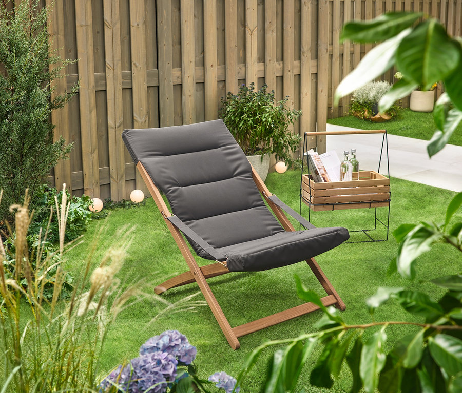 Na zelenom trávniku stojí debnička na bylinky s držadlom na prenášanie »Elin« vedľa ležadla.