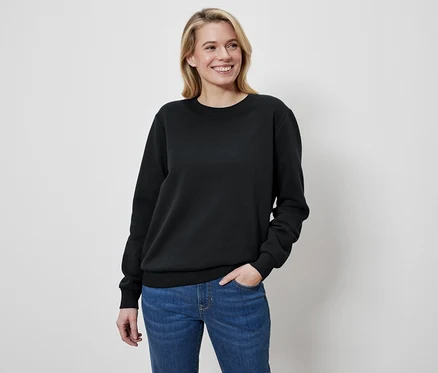 Žena s blond vlasmi má na sebe čierny sveter a džínsy.