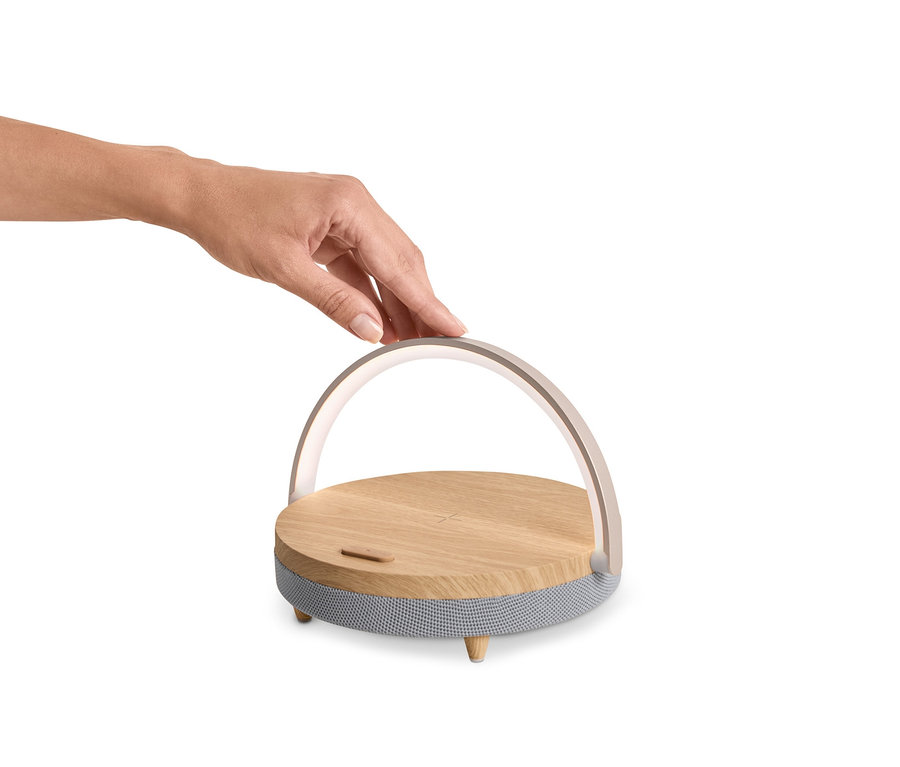 Ruka sa dotýka reproduktora s bluetooth, bezdrôtovou nabíjačkou a nočným svetlom s LED.