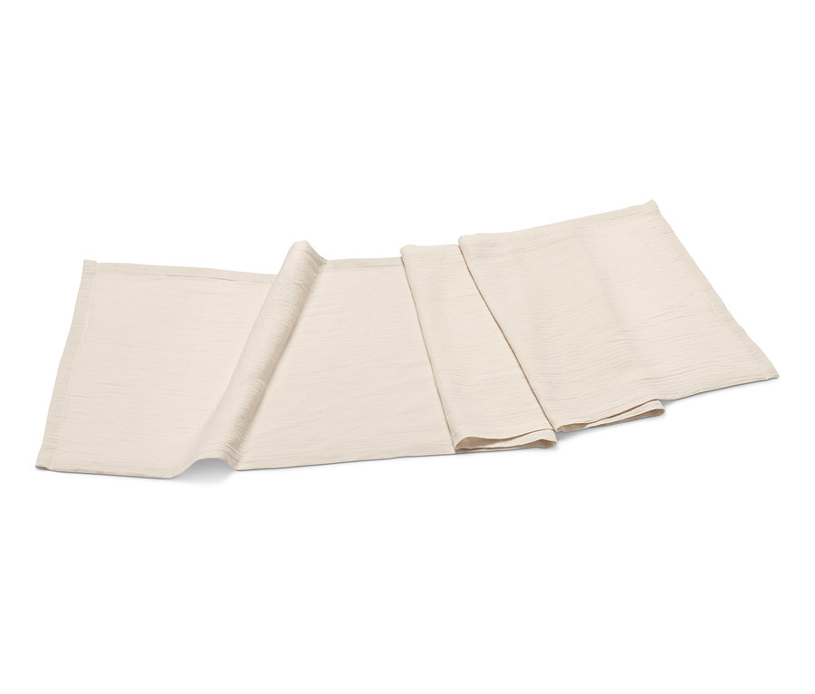 Béžový behúň na stôl z mušelínu leží zložený na bielom pozadí.