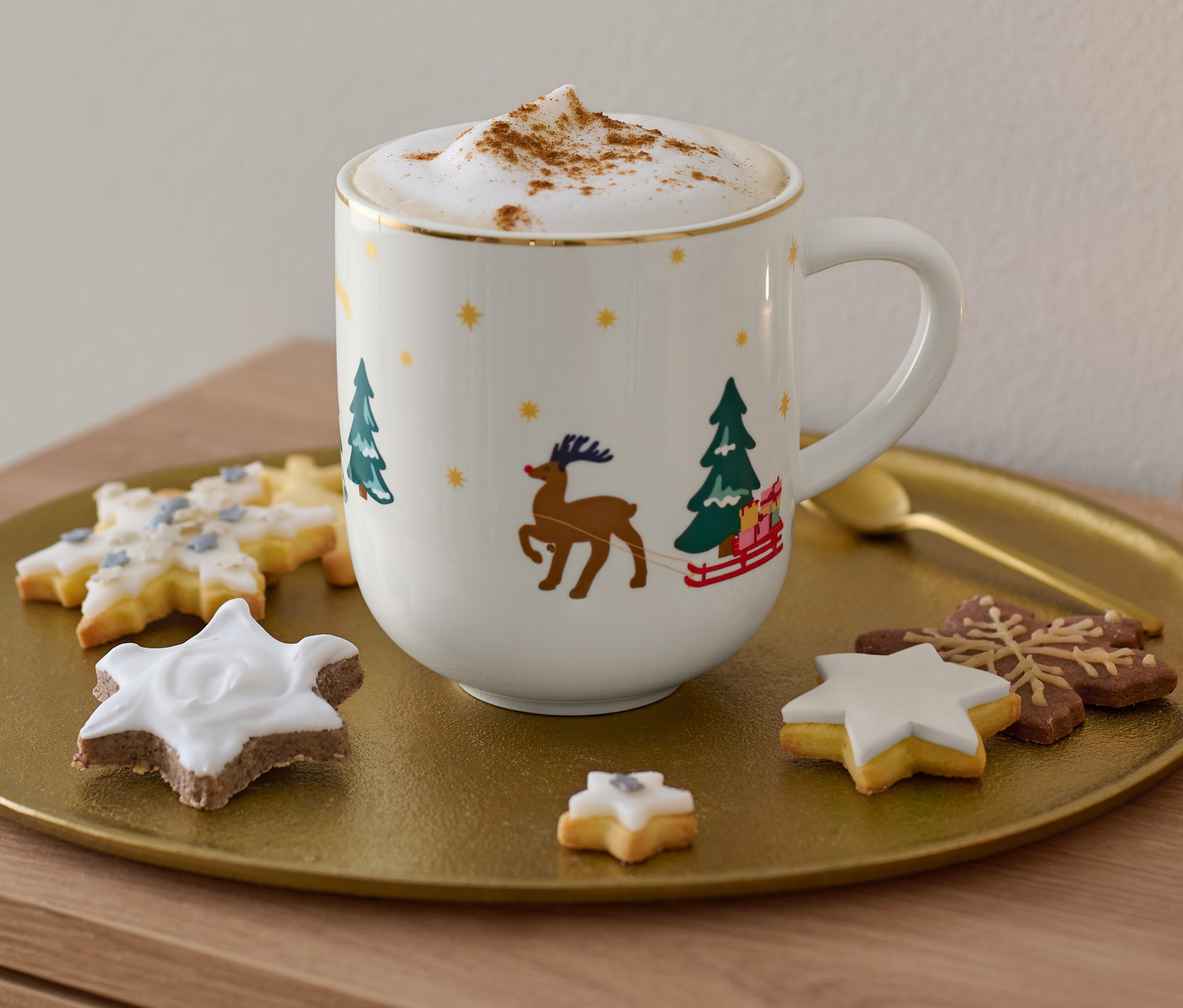 Na zlatom podnose je veľký hrnček s lesklým zlatým dekorom, cappuccino a cukrovinky.