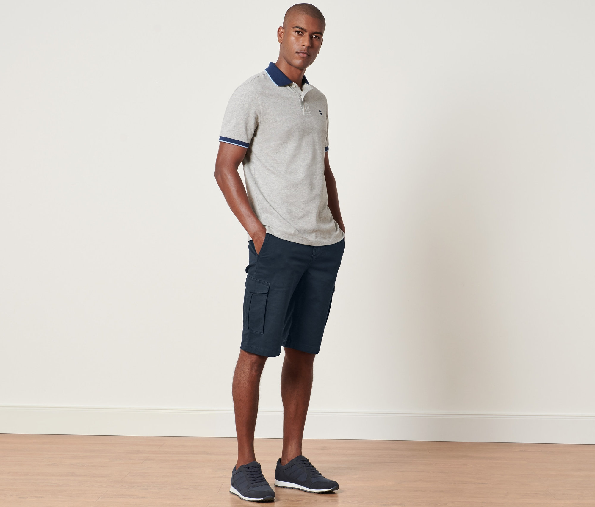 Muž stojí a má ruky vo vreckách námorníckych cargo šortiek.