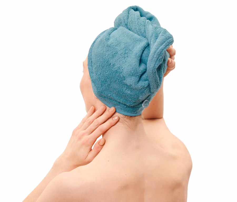 Žena si upravuje akvamarínový uterákový turban na hlave.