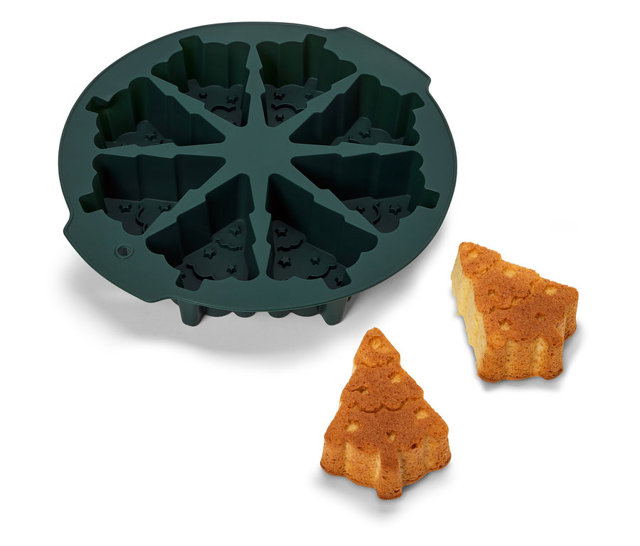 Zelená silikónová forma na pečenie v tvare vianočného stromčeka s dvoma upečenými stromčekmi vedľa.