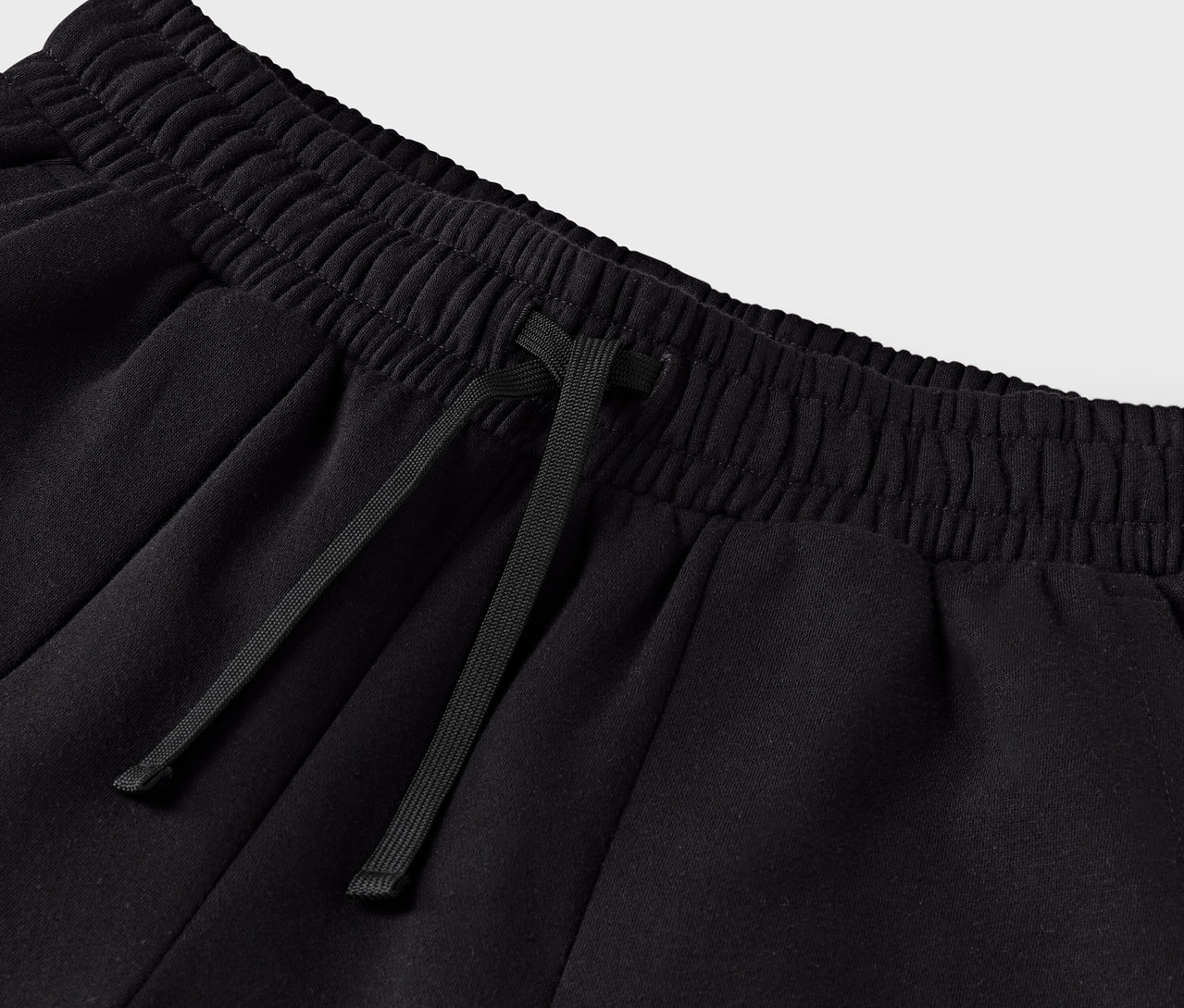 Detail čiernej teplákovej súpravy so sťahovacou šnúrkou v páse.