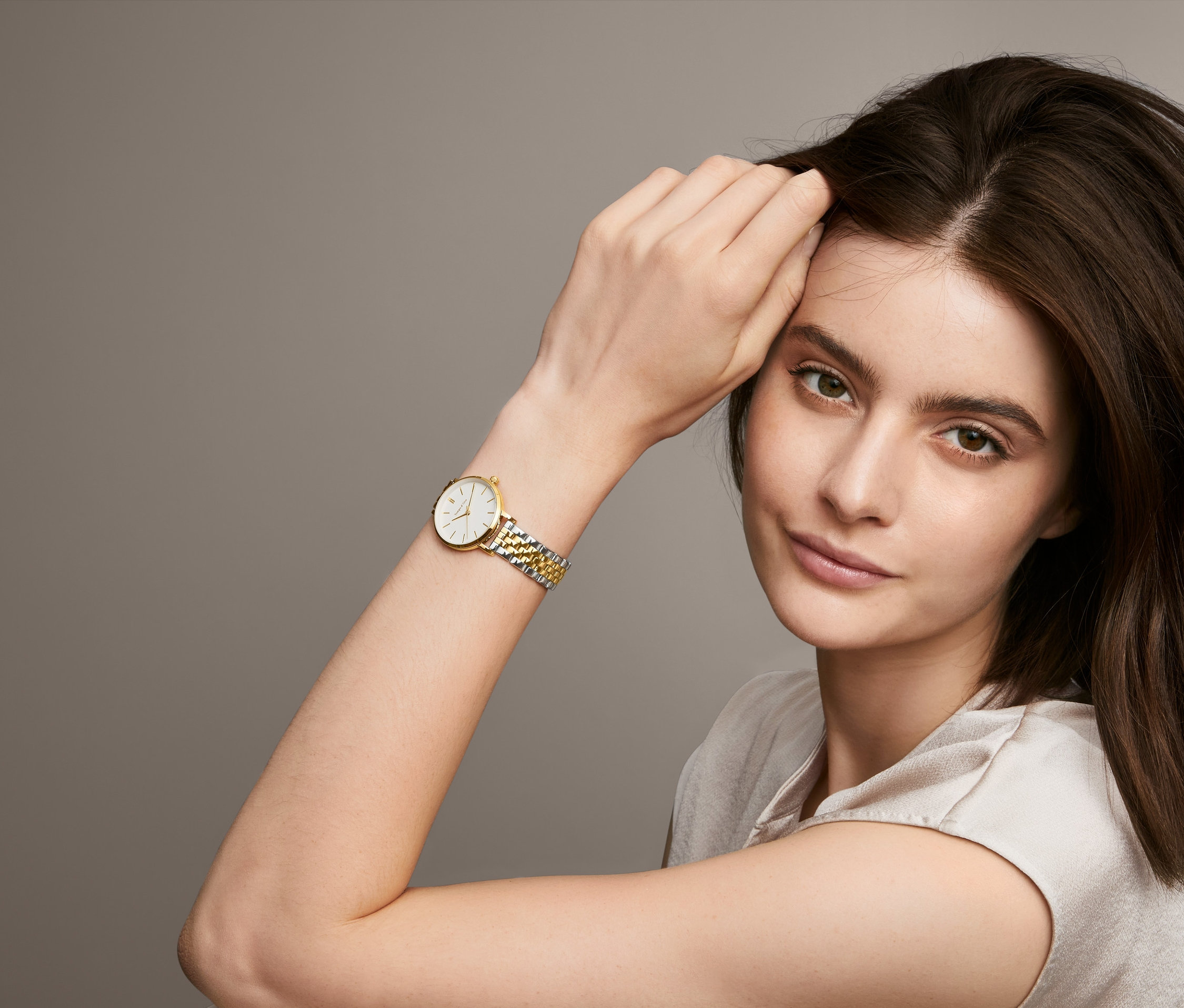 Portrét ženy s dámskymi hodinkami s dvojfarebným remienkom z ušľachtilej ocele.