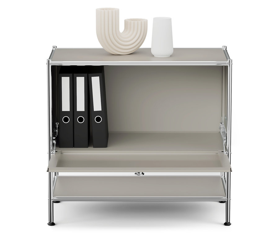 Sivá skrinka s chrómovaným rámom, na hornej poličke sú dve biele vázy a v hornej priehradke sú tri čierne zakladače.