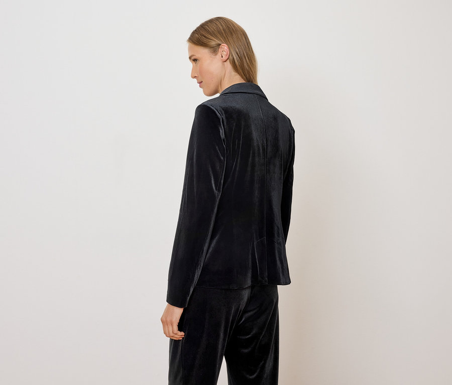 Žena má na sebe zamatové sako a nohavice.