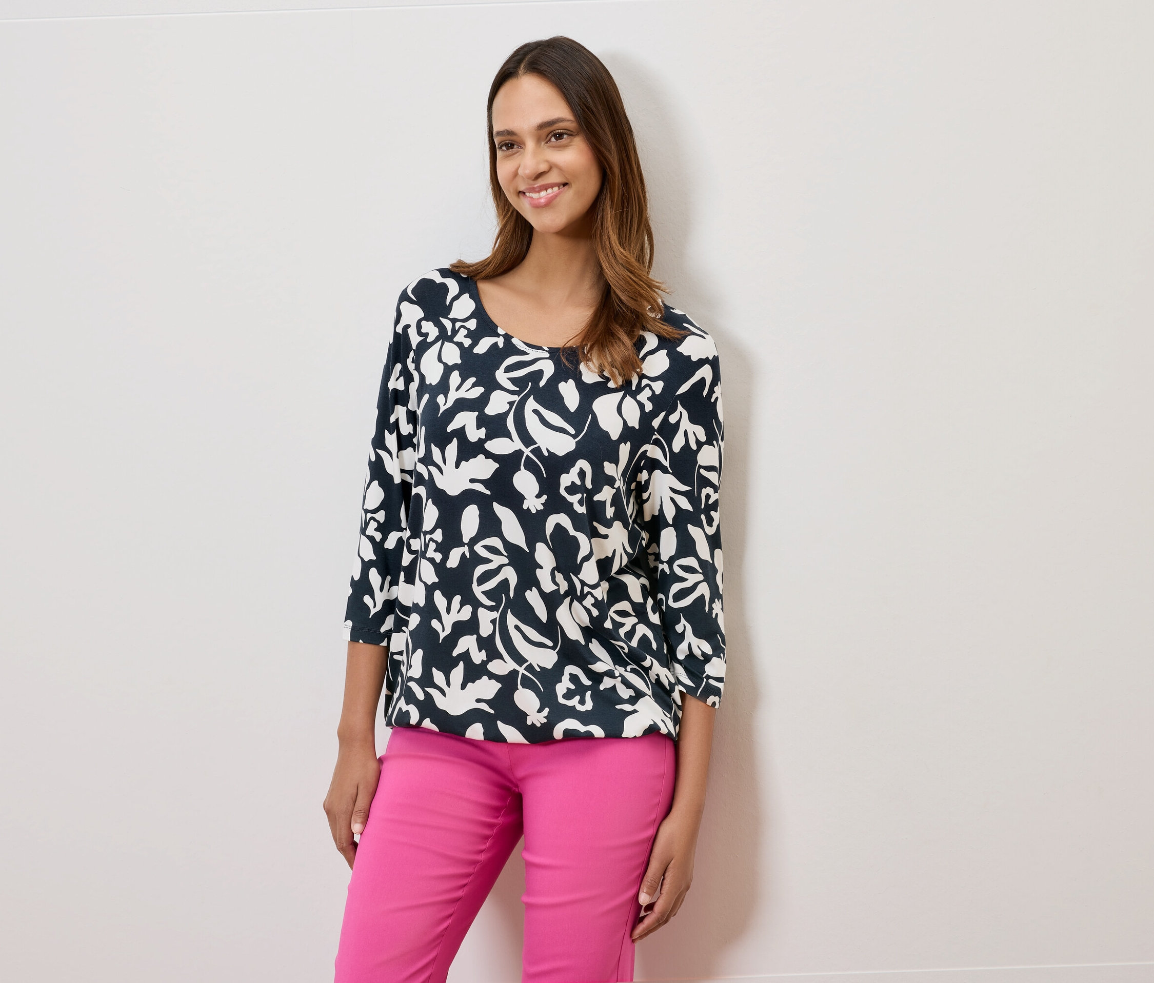 Žena má na sebe tmavomodrú blúzku s kvetinovou potlačou a ružové nohavice.