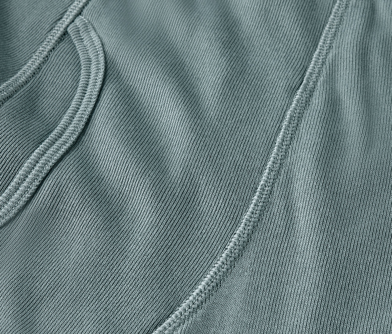 Detail modrozelenej látky s vreckom a švom.