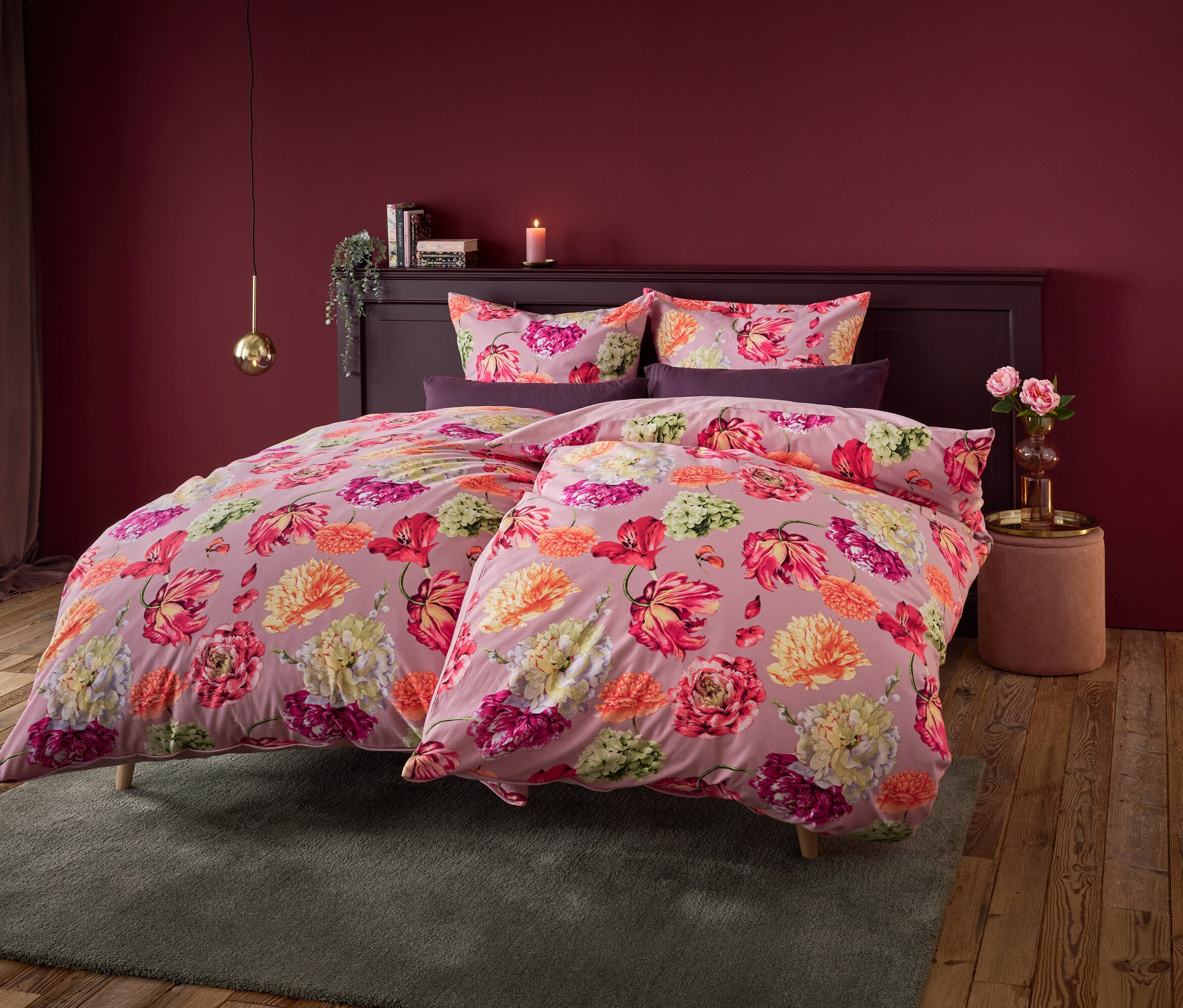 Kvetinové obliečky na posteli s tmavočervenou stenou v pozadí.