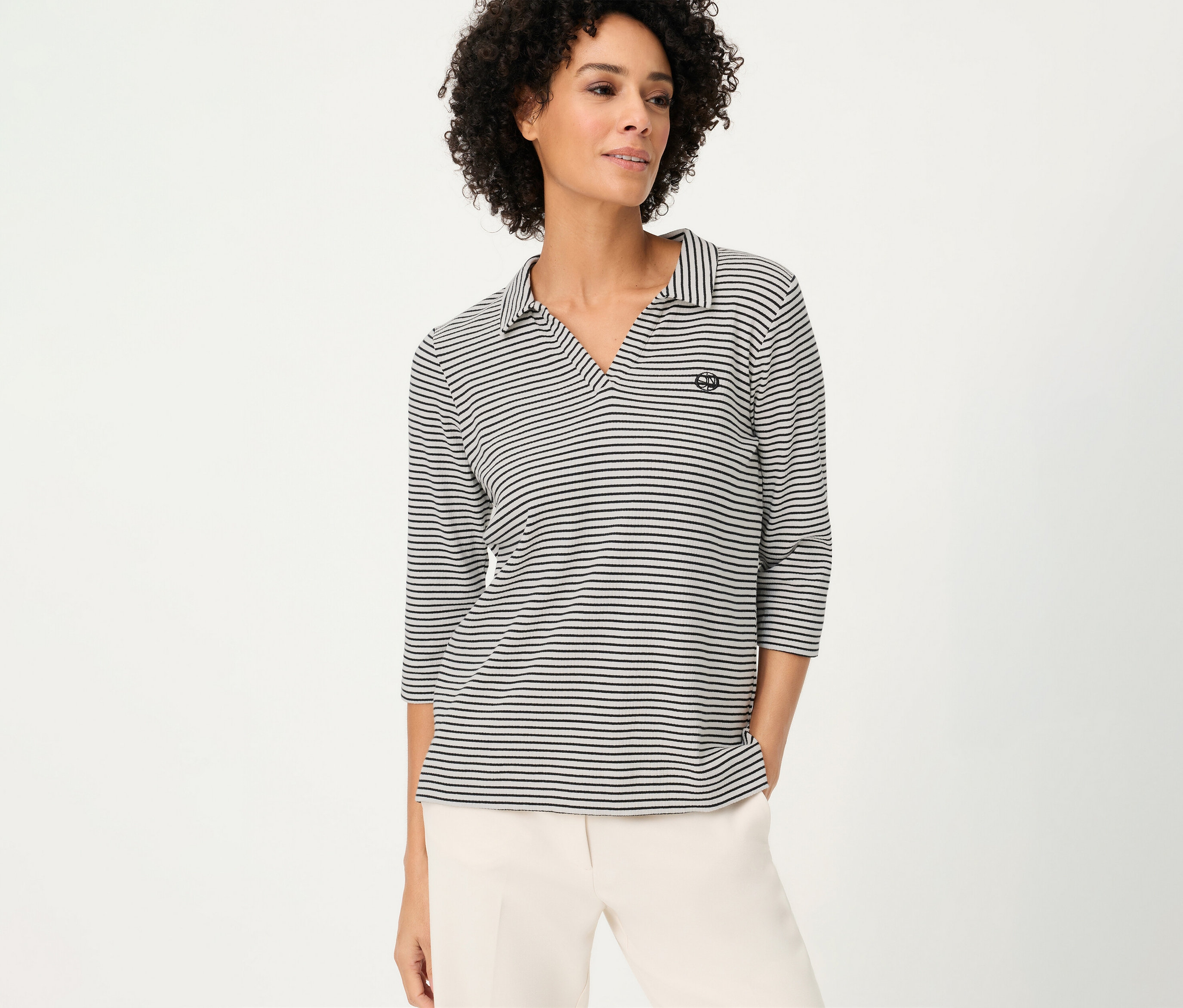 Žena nosí pruhovanú polokošeľu Olsen s trojštvrťovými rukávmi a svetlé nohavice.
