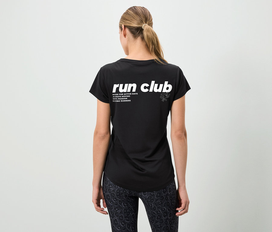 Pohľad zozadu na ženu s konským chvostom v čiernom tričku s nápisom "run club" a vzorovaných legínach.
