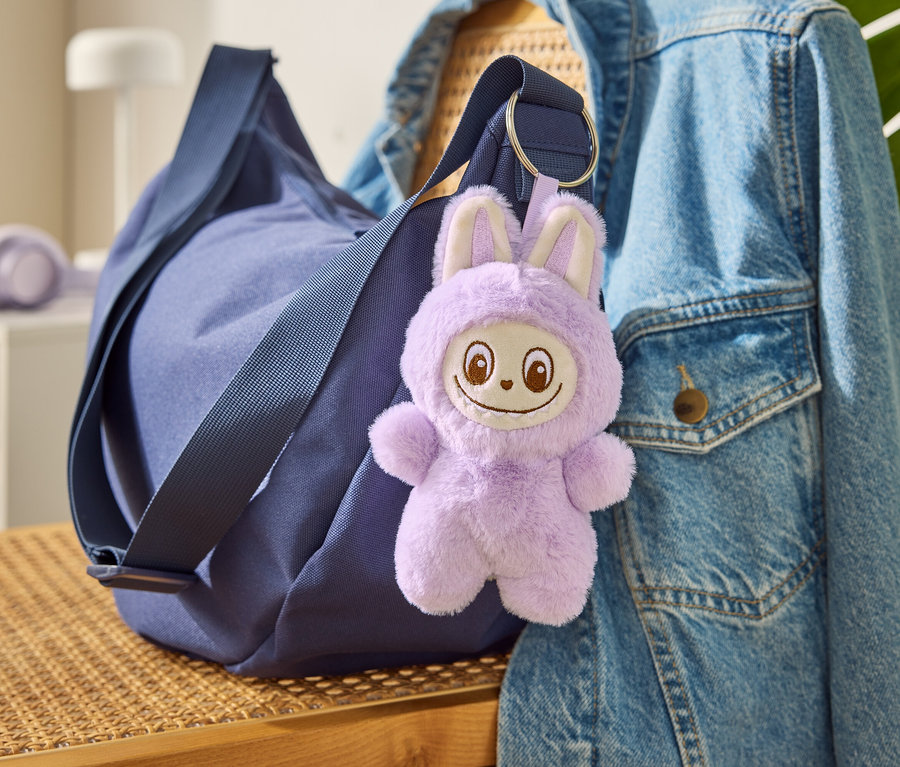 Modrá taška s príveskom na kľúče »Tchibobo« visí na džínsovej bunde.