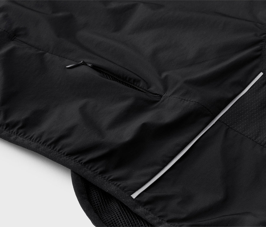 Detailný záber na čiernu vestu s vreckom na zips a reflexnými prvkami.