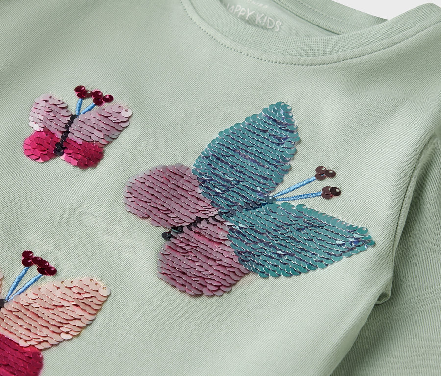 Svetlozelené tričko s dlhým rukávom a flitrovými motýľmi.