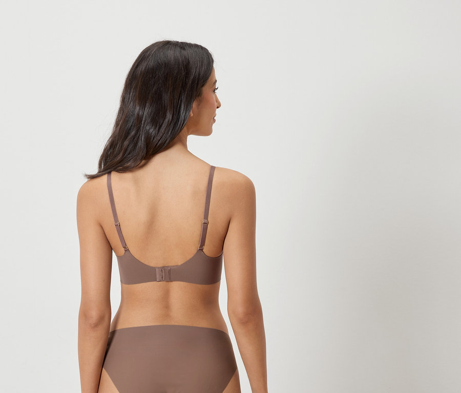 Pohľad zozadu na ženu s tmavými vlasmi, ktorá má na sebe hnedú podprsenku a nohavičky.