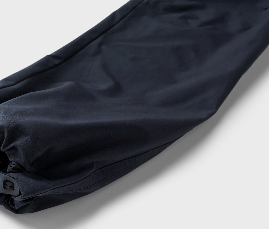 Detailný záber na námornícku modrú nohavicu s elastickým lemom a nastaviteľným prepínacím uzáverom na neutrálnom pozadí.