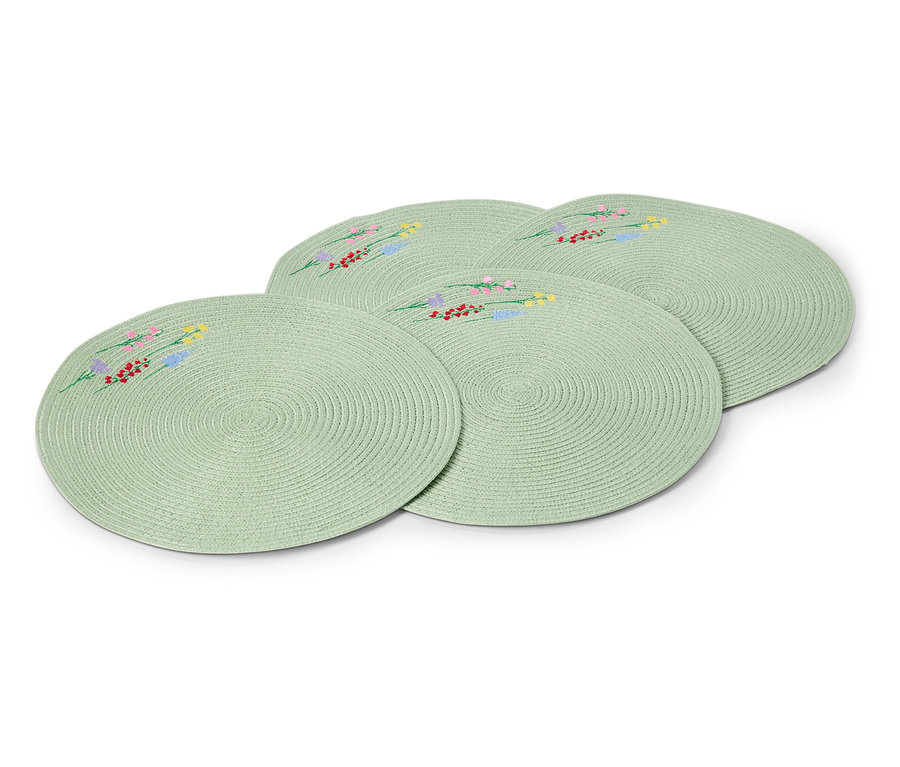 Štyri okrúhle, svetlozelené prestierania s vyšívanými kvetinovými vzormi ležia na sebe.