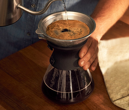 Muž naleje vodu do sklenenej karafy BEEM Pour Over 0,75 l s filtrom na kávu.