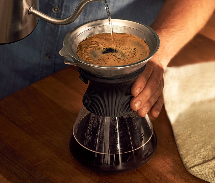 Muž naleje vodu do sklenenej karafy BEEM Pour Over 0,75 l s filtrom na kávu.