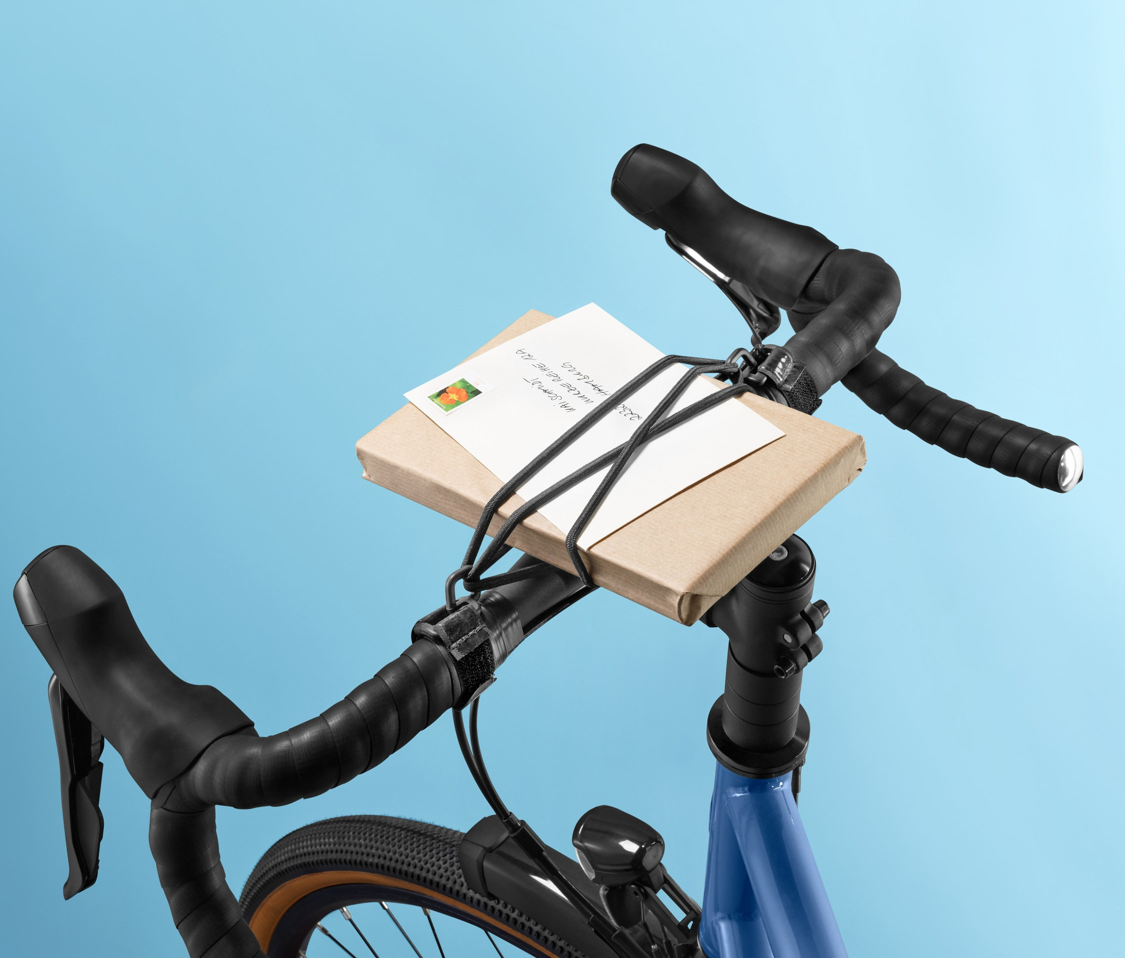 Balík na riadidlách bicykla upevnený upínacím popruhom na riadidlá.