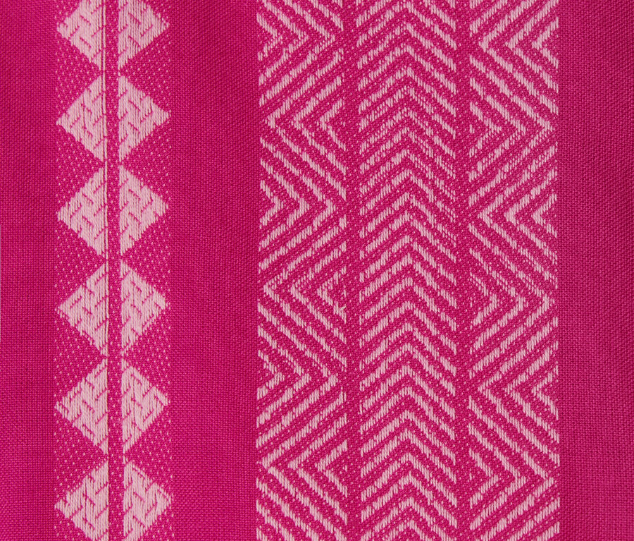 Detail tkaniny ružových šiat s ikatovým vzorom.