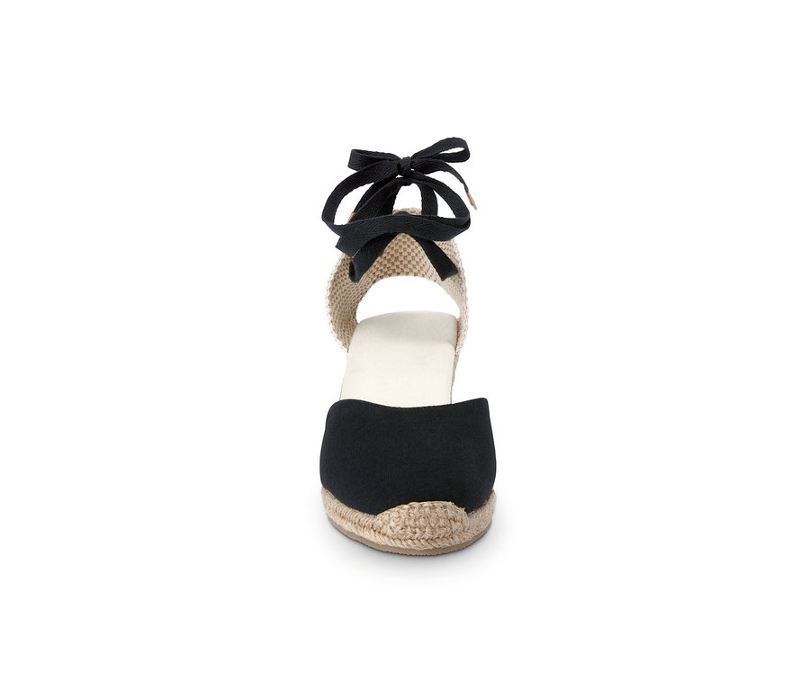 Detail dámskej espadrilky s klinovým podpätkom a čiernou stuhou.