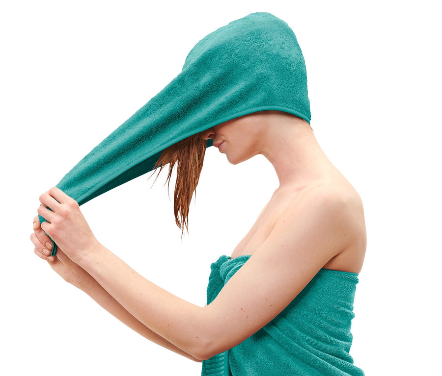 Žena si nasadzuje akvamarínový uterákový turban.