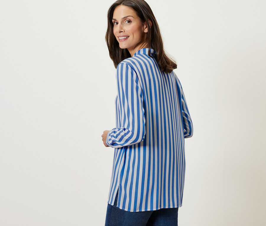 Žena sa pozerá cez plece a má na sebe prúžkovanú blúzku.