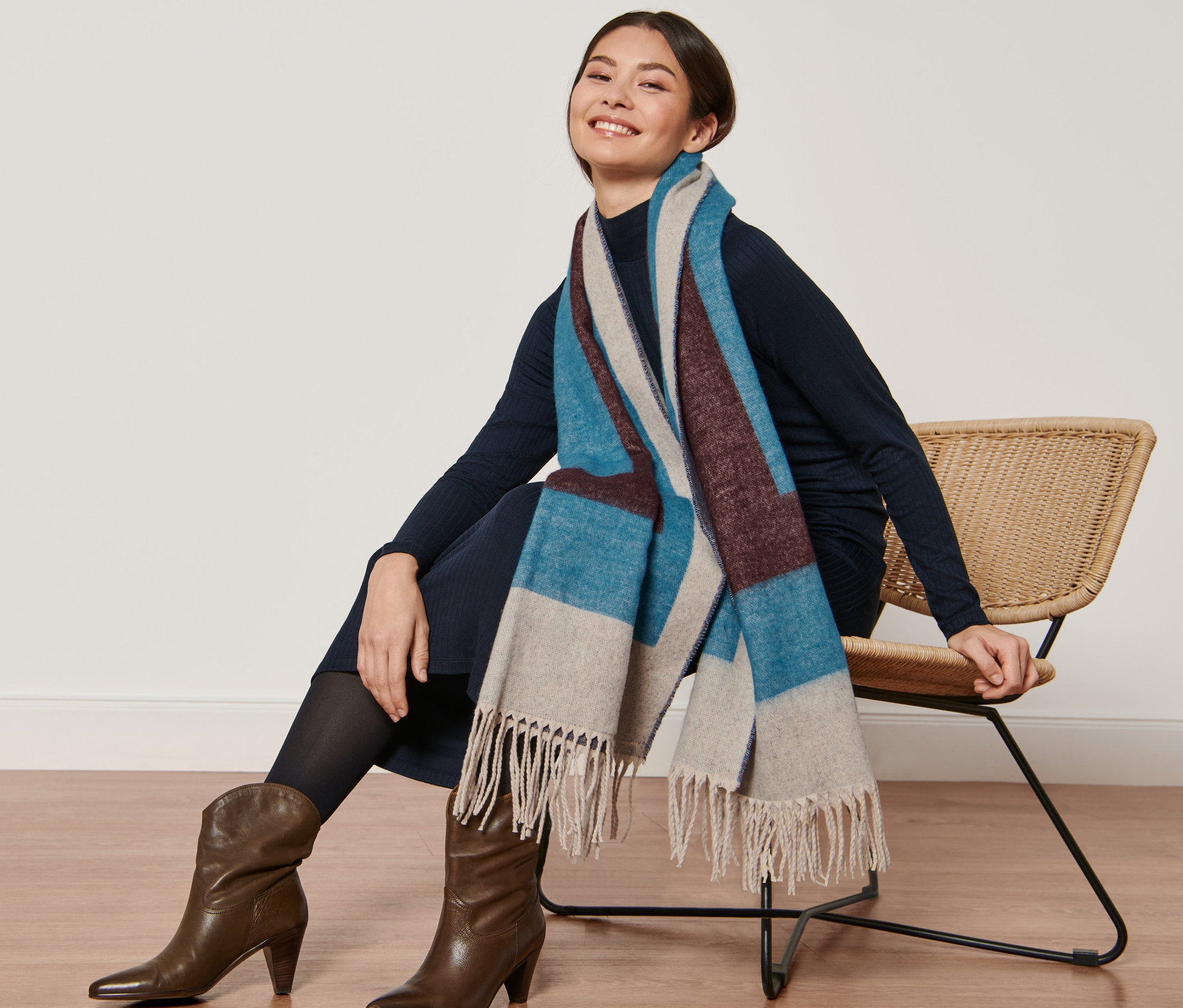 Žena sedí na stoličke a má na sebe tkaný šál.