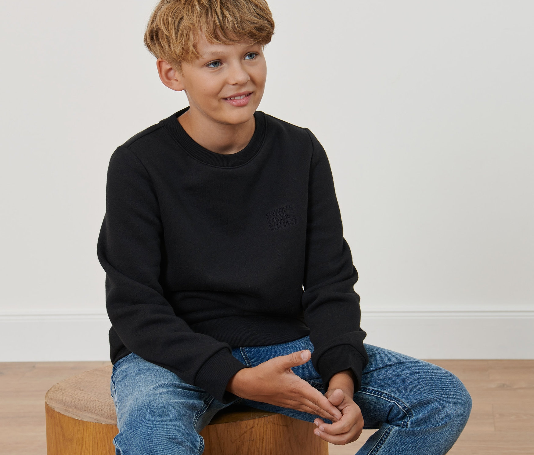 Chlapec sedí na stoličke a má na sebe detský pulóver.