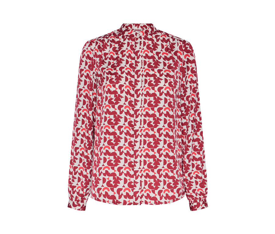 Detail dámskej blúzky s červenou geometrickou potlačou.