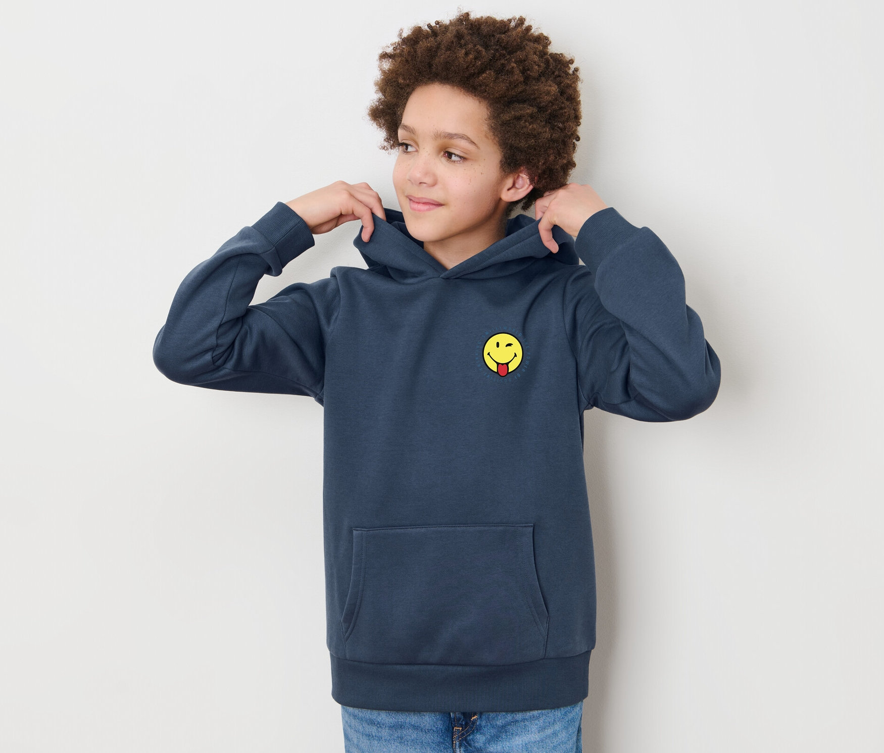 Chlapec si upravuje kapucňu na detskej mikine z teplákoviny »Smiley«.