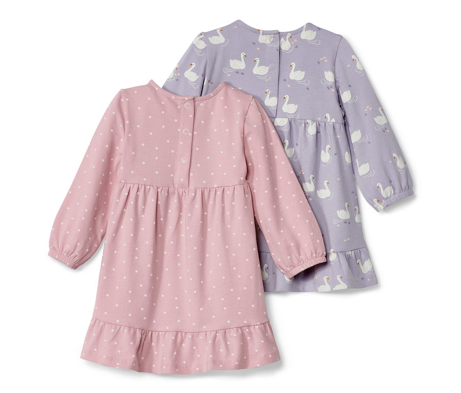 Dvoje dojčenské džersejové šaty: jedny ružové s bielymi bodkami a jedny fialové s potlačou labutí.
