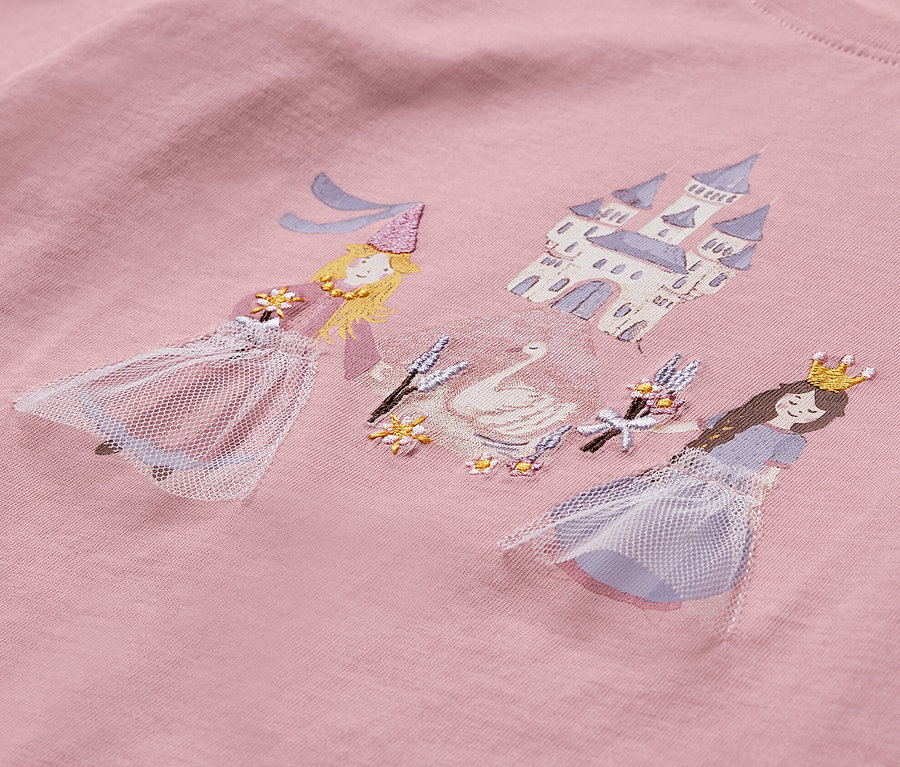 Detail ružového trička s potlačou dvoch princezien, labute a hradu.