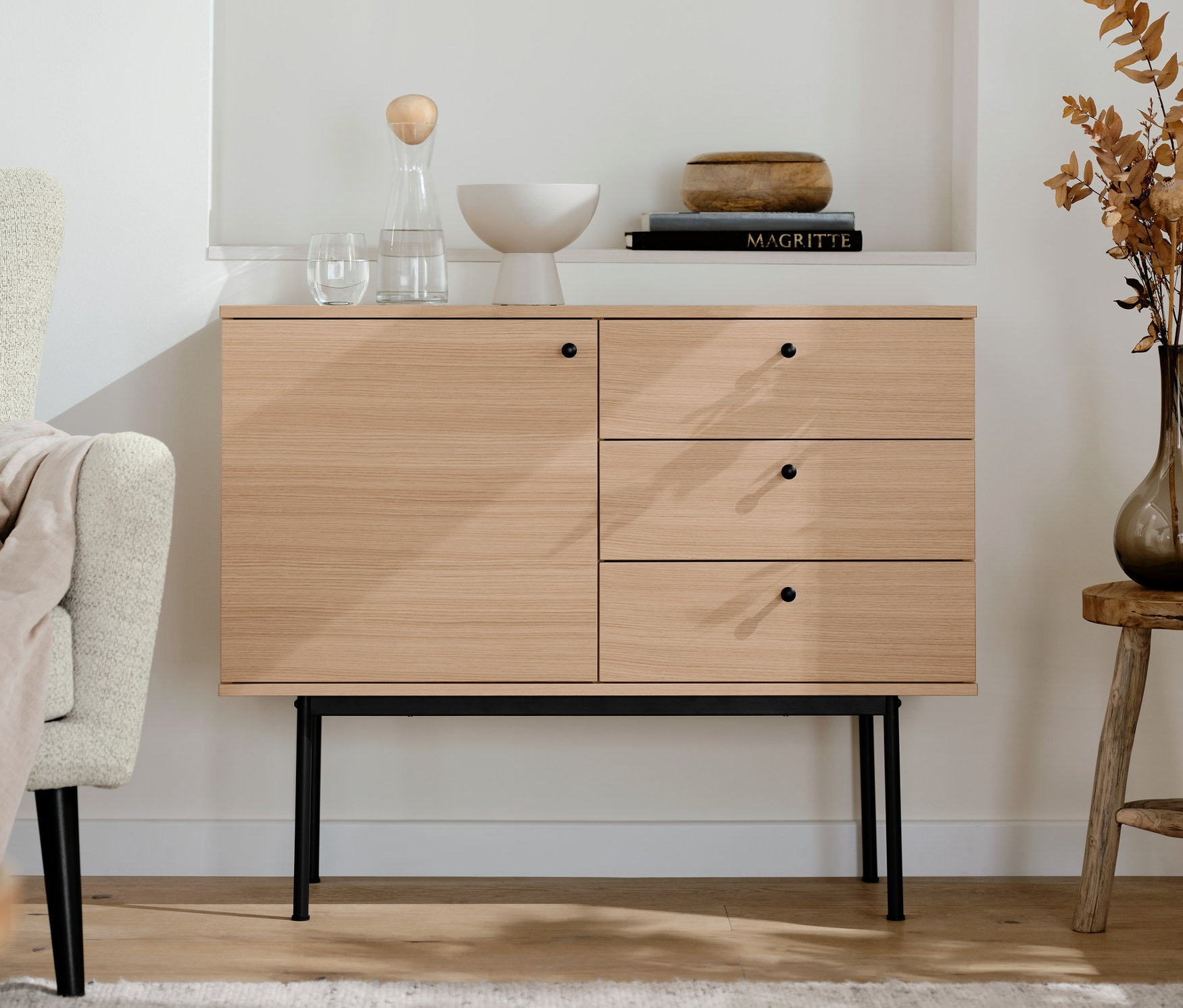 V obývacej izbe stojí konzolový stolík »Finnsbo« so zásuvkami. Nad ním sú police s dekoráciami.