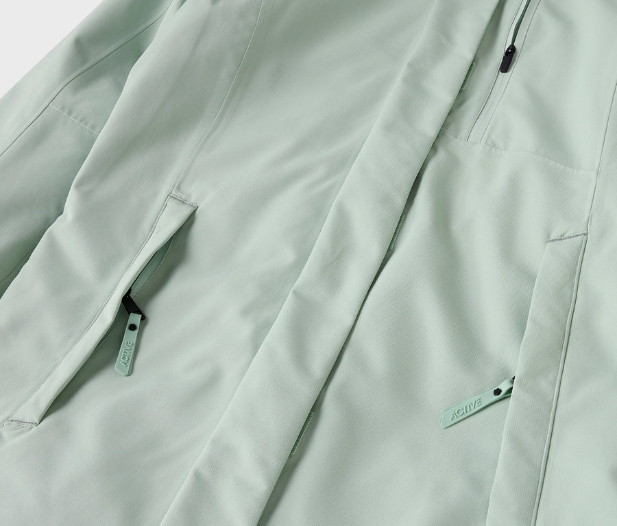 Detail svetlozelenej bundy s vreckami na zips.