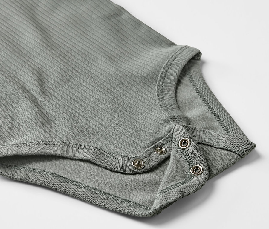 Detail sivého rebrovaného body s dlhým rukávom pre bábätká so zapínaním na patentky.