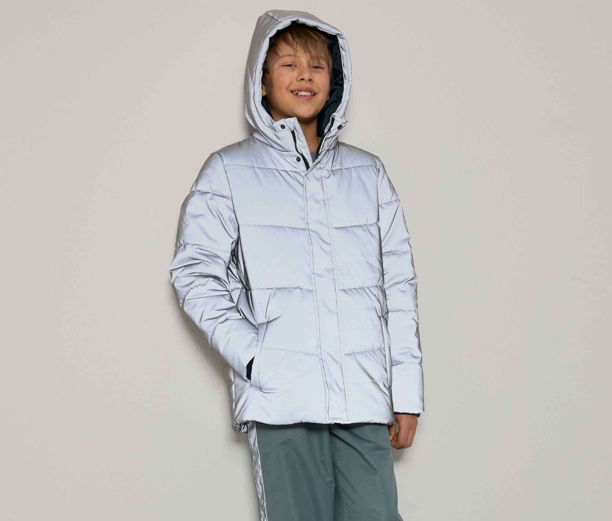 Chlapec má na sebe reflexnú prešívanú bundu pre deti.