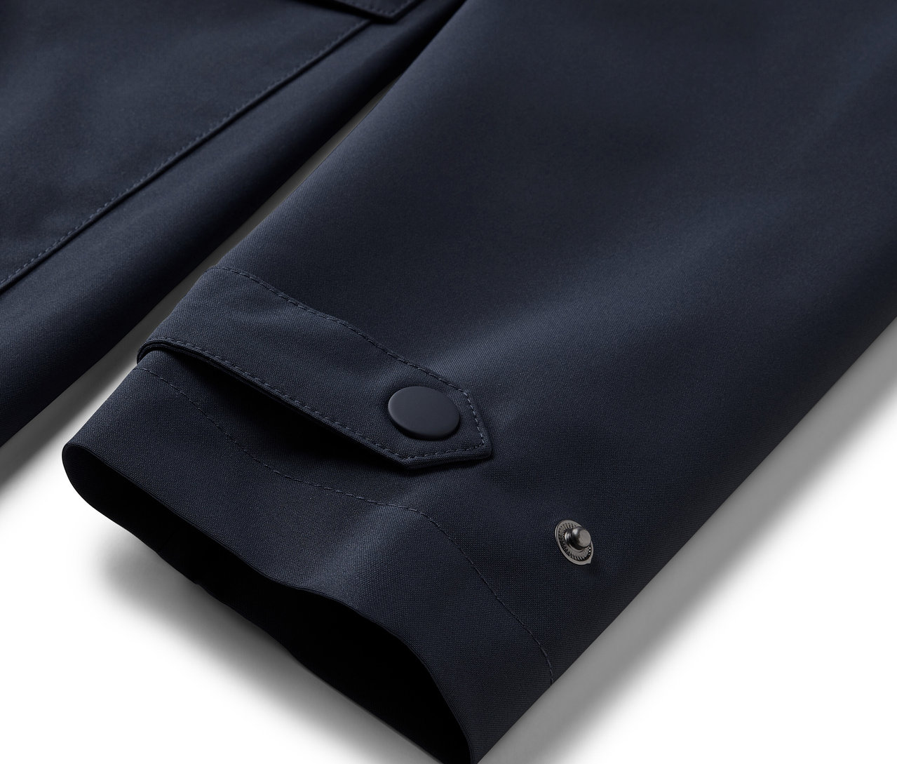 Detail rukávu modrého nepremokavého trenčkotu.