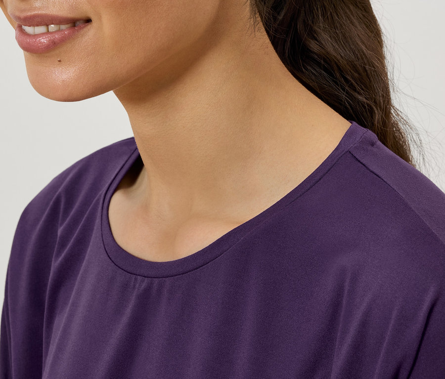 Detail ženy nosiacej fialové tričko s okrúhlym výstrihom.