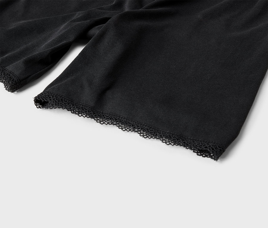 Detailný záber rukávov čiernej látky s čipkovaným okrajom.