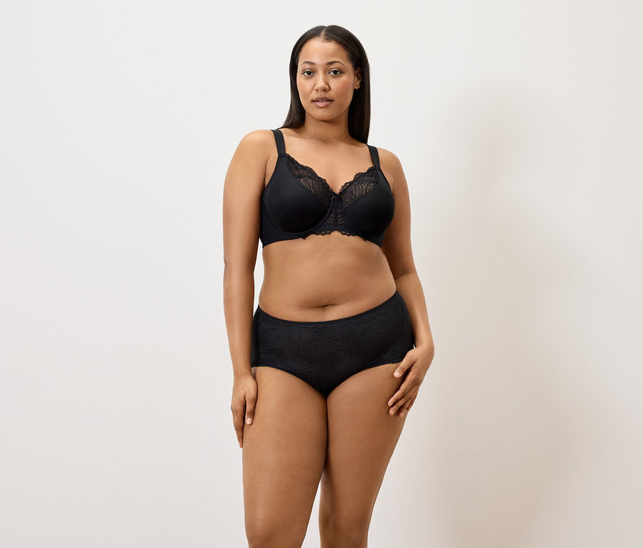 Žena má na sebe čiernu zmenšujúcu podprsenku a čierne nohavičky (5 ks) na bielom pozadí.