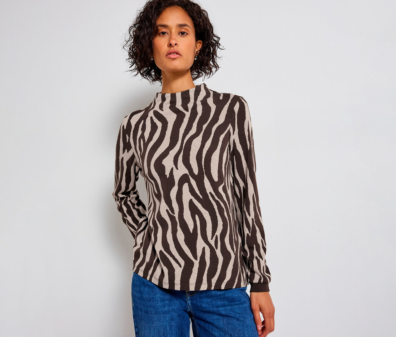 Žena má na sebe žakárovú košeľu Street One so vzorom zebry a modré džínsy.